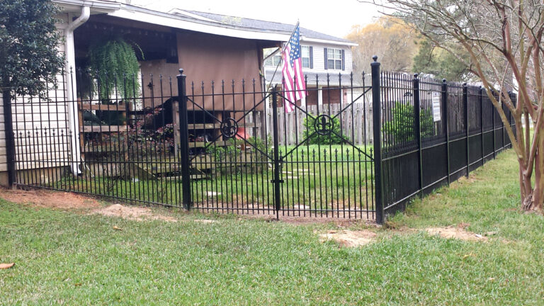 custom backyard fence and wrought iron gate with fleur de lis ornamente